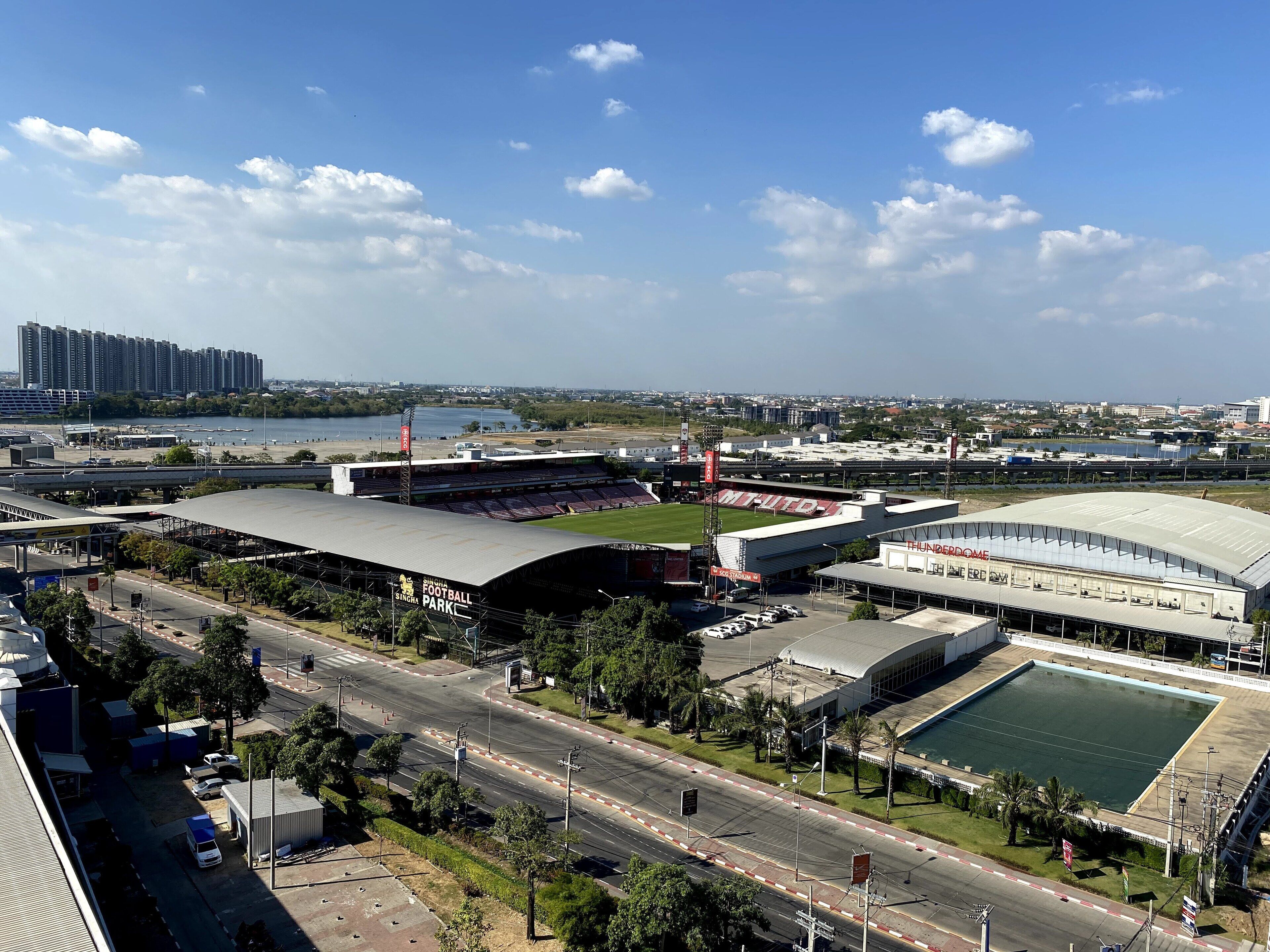 A stadium with a large seating area and a smaller enclosed area, surrounded by roads and greenery.