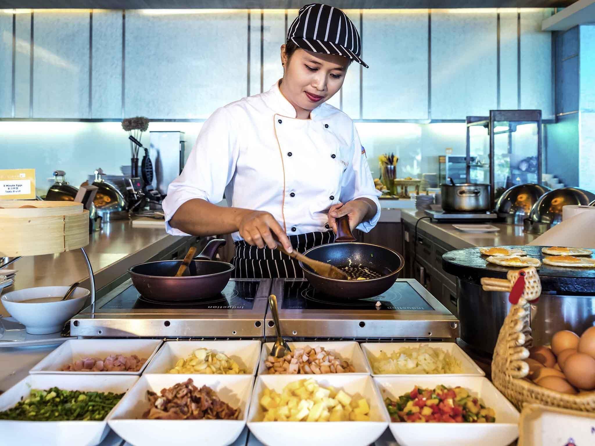 A chef preparing food in a kitchen with various ingredients and cooking utensils.