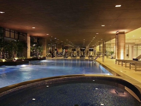 Una piscina techada, sillones reclinables de piscina. Novotel Bangkok IMPACT
