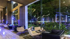 A modern indoor lounge area with seating, large windows, and a view of the outside. - Novotel Bangkok IMPACT (Pak Kret)