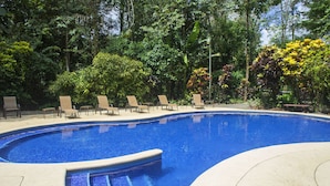 A swimming pool with a tiled edge, surrounded by lounge chairs and lush greenery. - Selva Verde Lodge (Puerto Viejo)