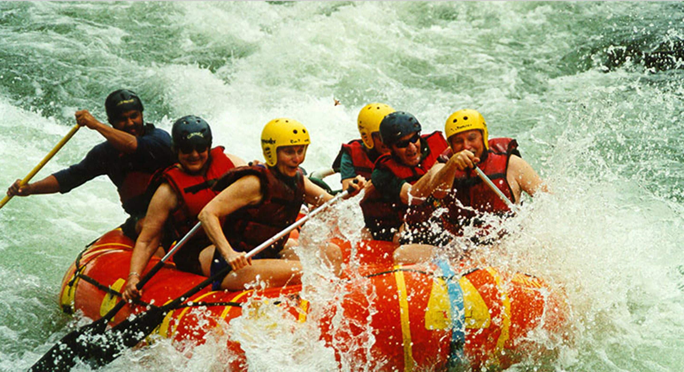 A group of people in a raft navigating through white water rapids.