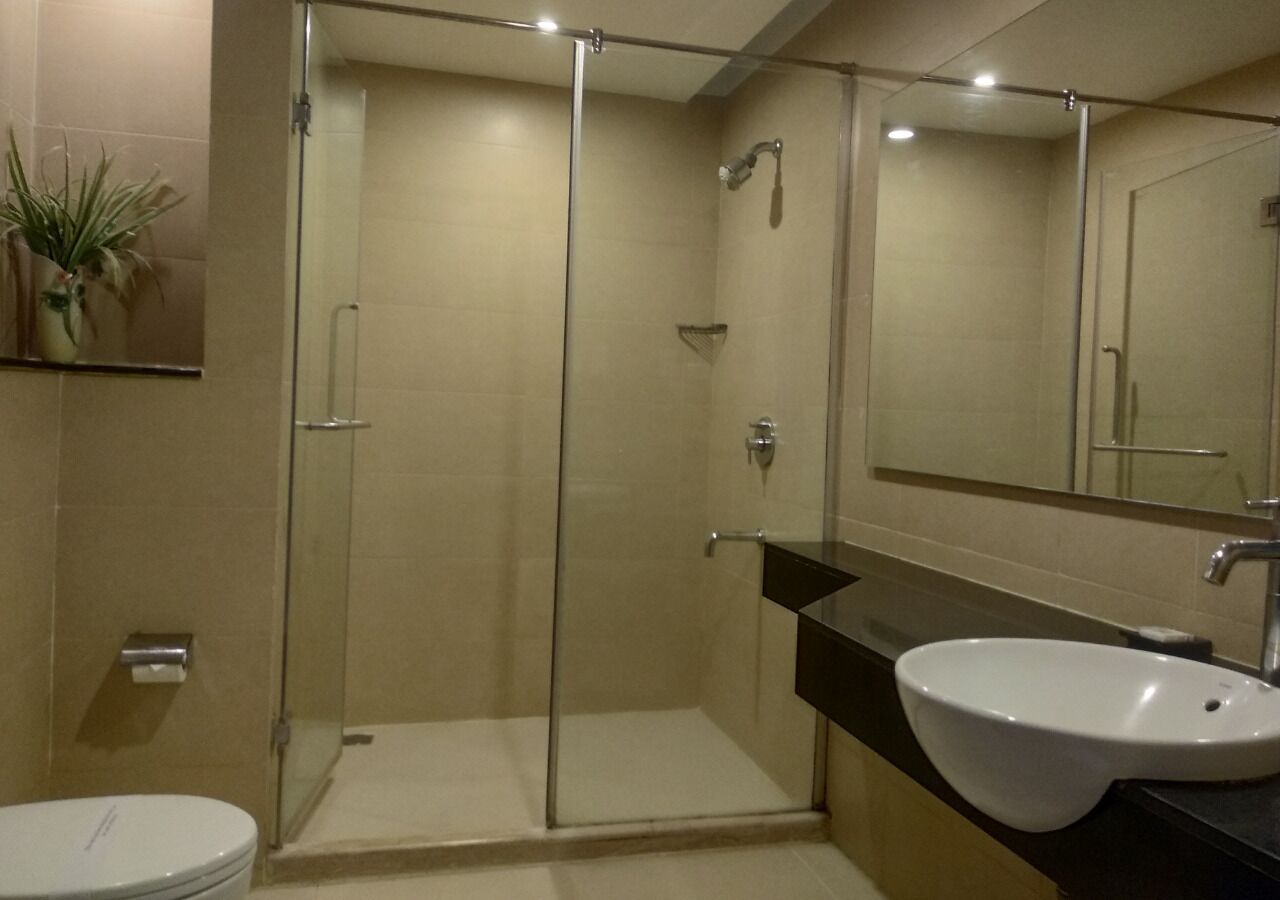 Un baño moderno con ducha de vidrio, lavamanos blanco y espejo sobre el lavamanos.