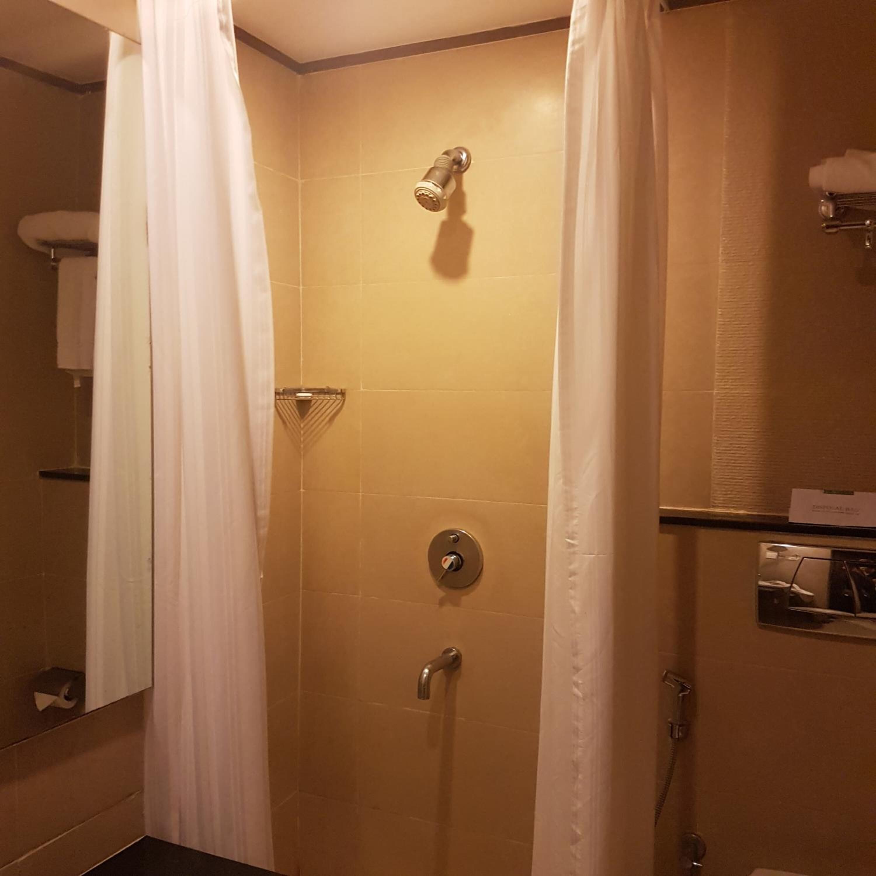 A bathroom with a shower, a towel rack, and a mirror.