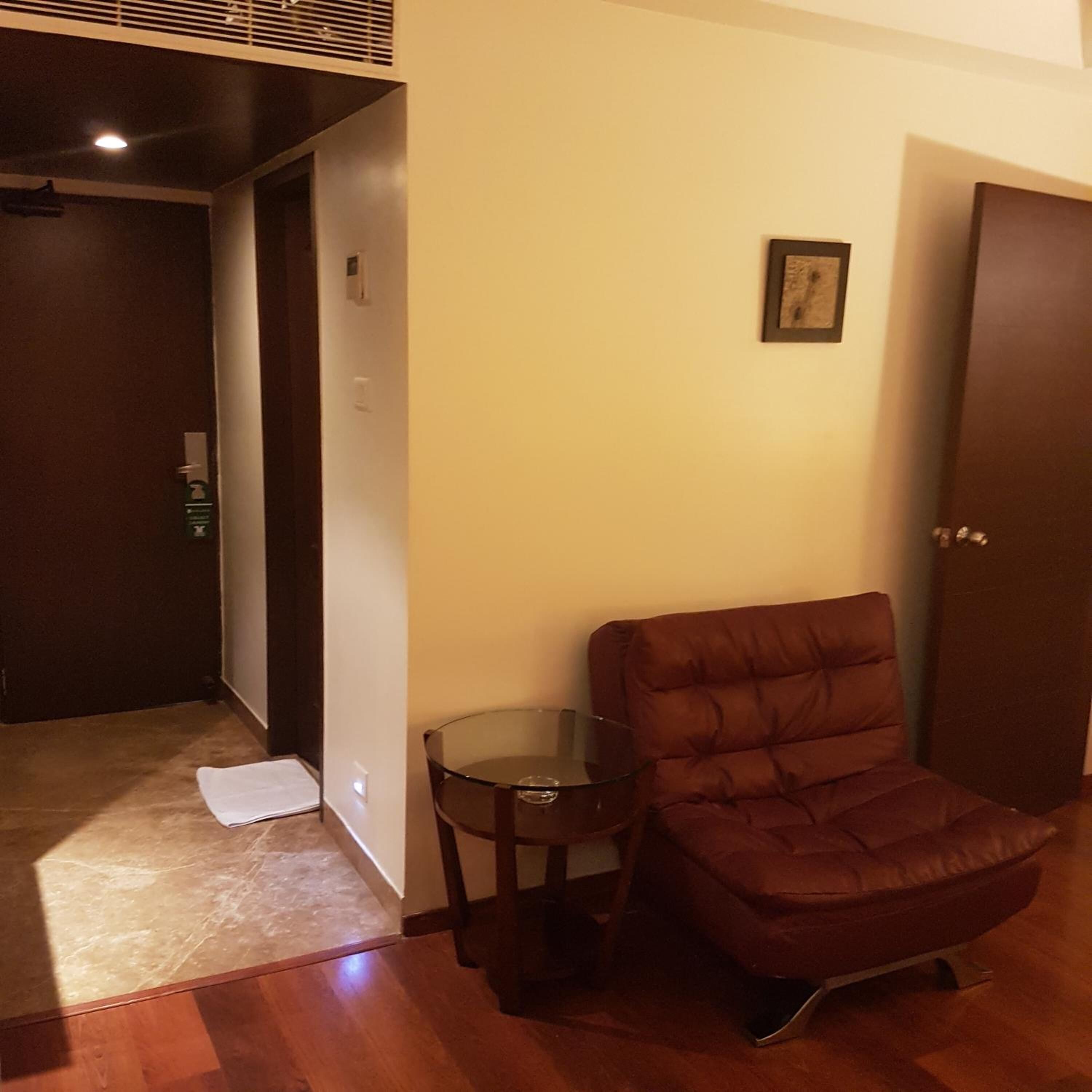A room with a brown leather chair, a small glass table, and a wooden door.