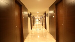A long, well-lit hallway with doors on both sides, leading to individual rooms.