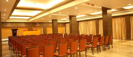 Un salón de conferencias con hileras de sillas, un atril y cortinas.