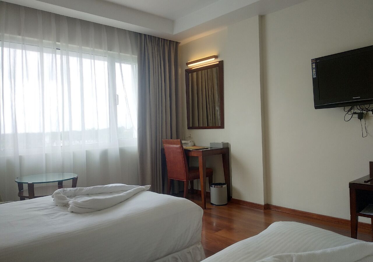 A hotel room with a bed, a desk, a chair, a television, and a window with curtains.