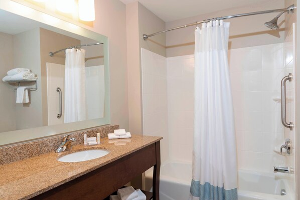 Baño con lavamanos de granito, espejo, toallero y ducha con cortina.