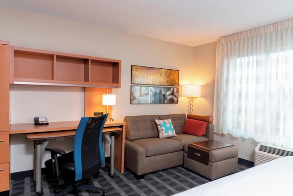 A hotel room with a desk, chair, sofa, and bed. - TownePlace Suites Fort Wayne North (Fort Wayne)