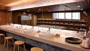 A long, modern bathroom with three sinks, wooden stools, and a large mirror. - Shiga Park Hotel (Yamanouchi)