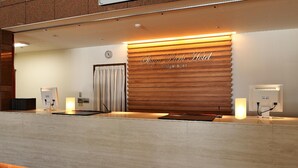 A reception desk with a wooden panel wall, a clock, and a sign reading "Shigakogen Hotel". - Shiga Park Hotel (Yamanouchi)