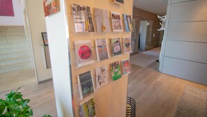 A hallway with a display of framed artwork on the wall and a plant in the foreground. - ART-Hotel Braun (Kirchheimbolanden)