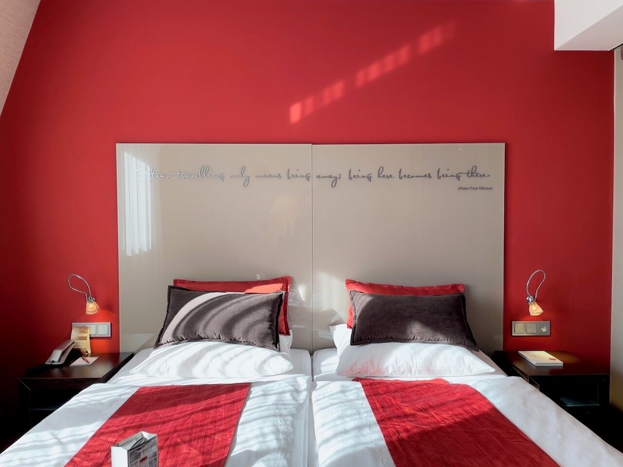 A double bed with a red and white bedspread, two bedside lamps, and a mirror above the bed.