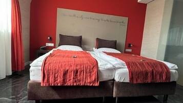 A modern hotel room with a large bed, red accents, and a marble floor.