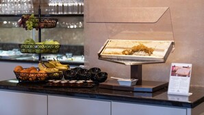 A buffet counter with a variety of fruits, a display case with food, and a menu sign. - ART-Hotel Braun (Kirchheimbolanden)