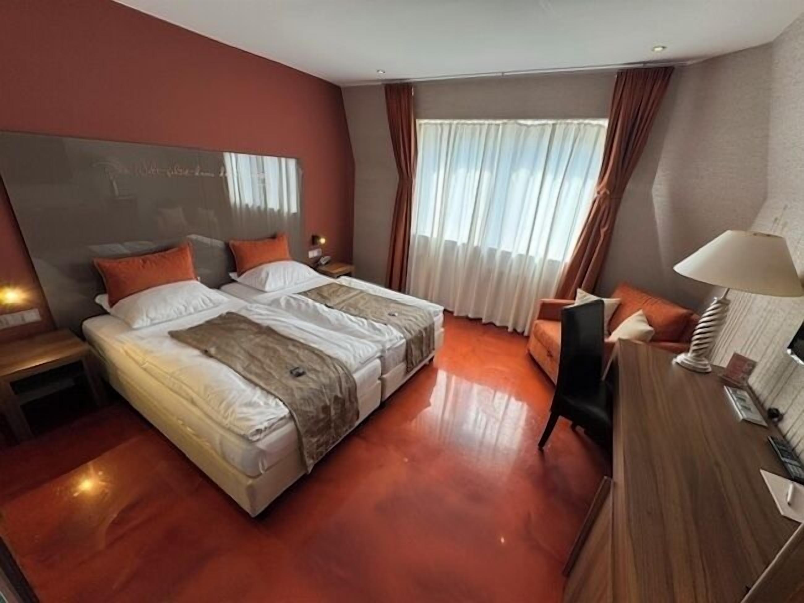 Habitación de hotel con cama doble, escritorio, silla y televisor.
