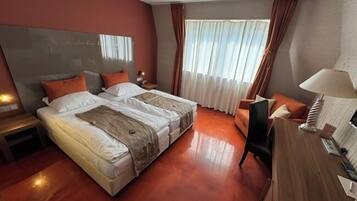 Habitación de hotel con cama doble, escritorio, silla y televisor.