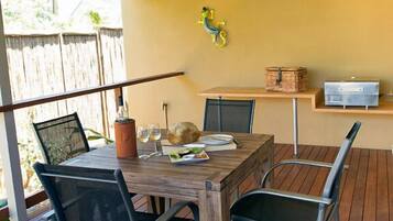 An outdoor dining area with a wooden table and chairs, a ceiling fan, and a wooden deck.