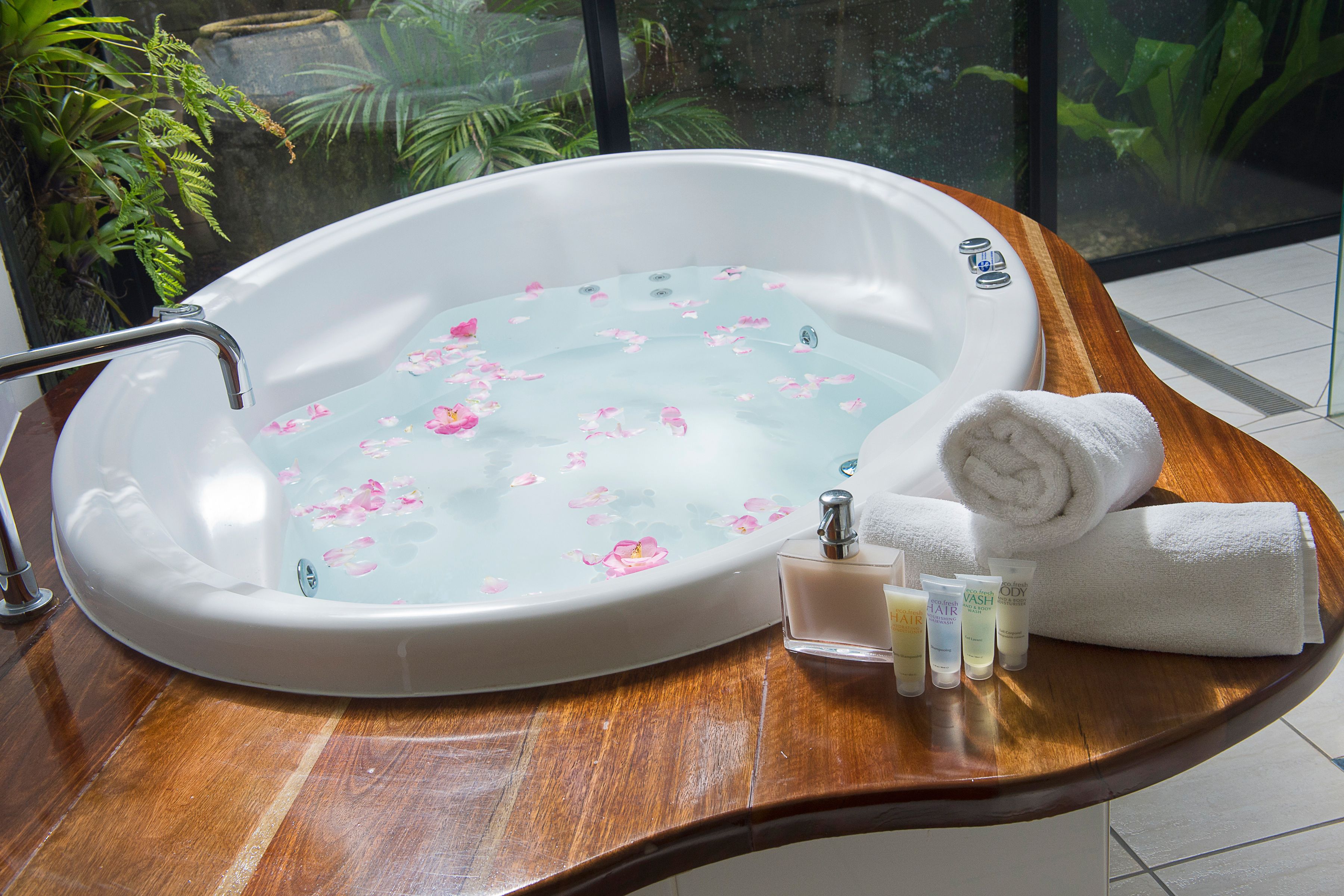 Eine Badewanne mit floralen Verzierungen, ein hölzerner Waschtisch und Pflegeprodukte.