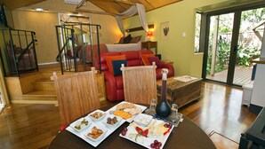 Una habitación amplia con una cama grande, una mesa de comedor con diversos alimentos y vistas al exterior.