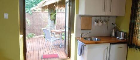 A compact kitchen with a built-in sink, white cabinets, and a small refrigerator.