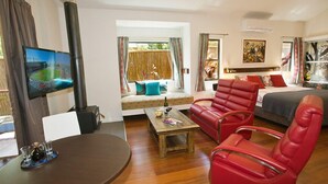 Una sala moderna con un sofá, un sillón rojo, una mesa de centro de madera y un televisor.