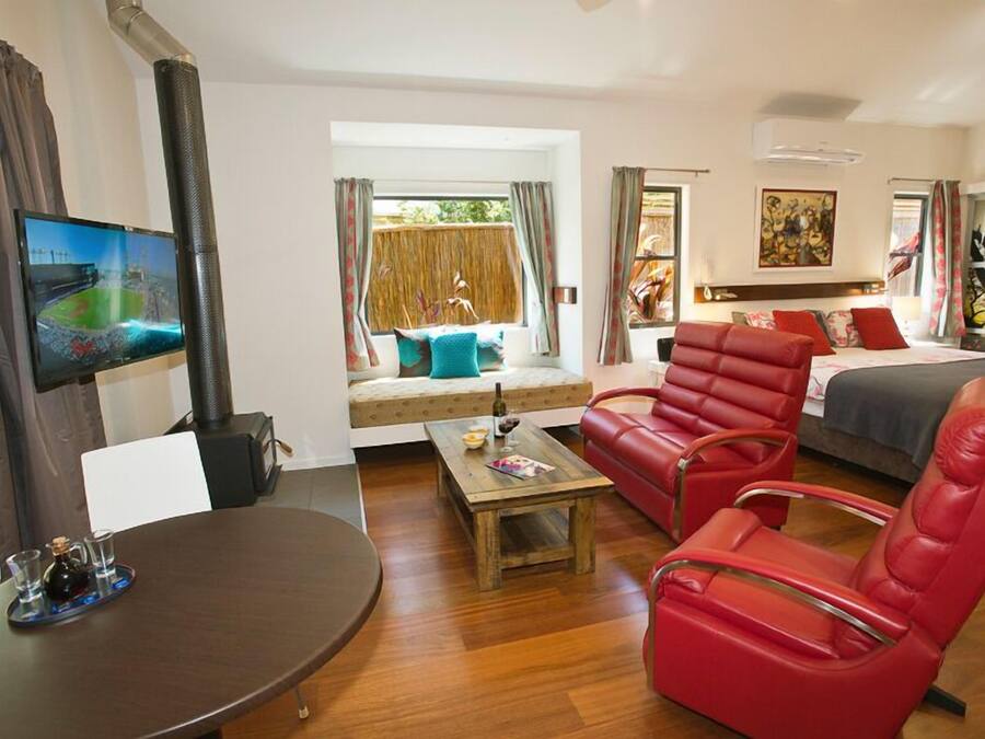 A modern living room with a sofa, a red armchair, a wooden coffee table, and a television.