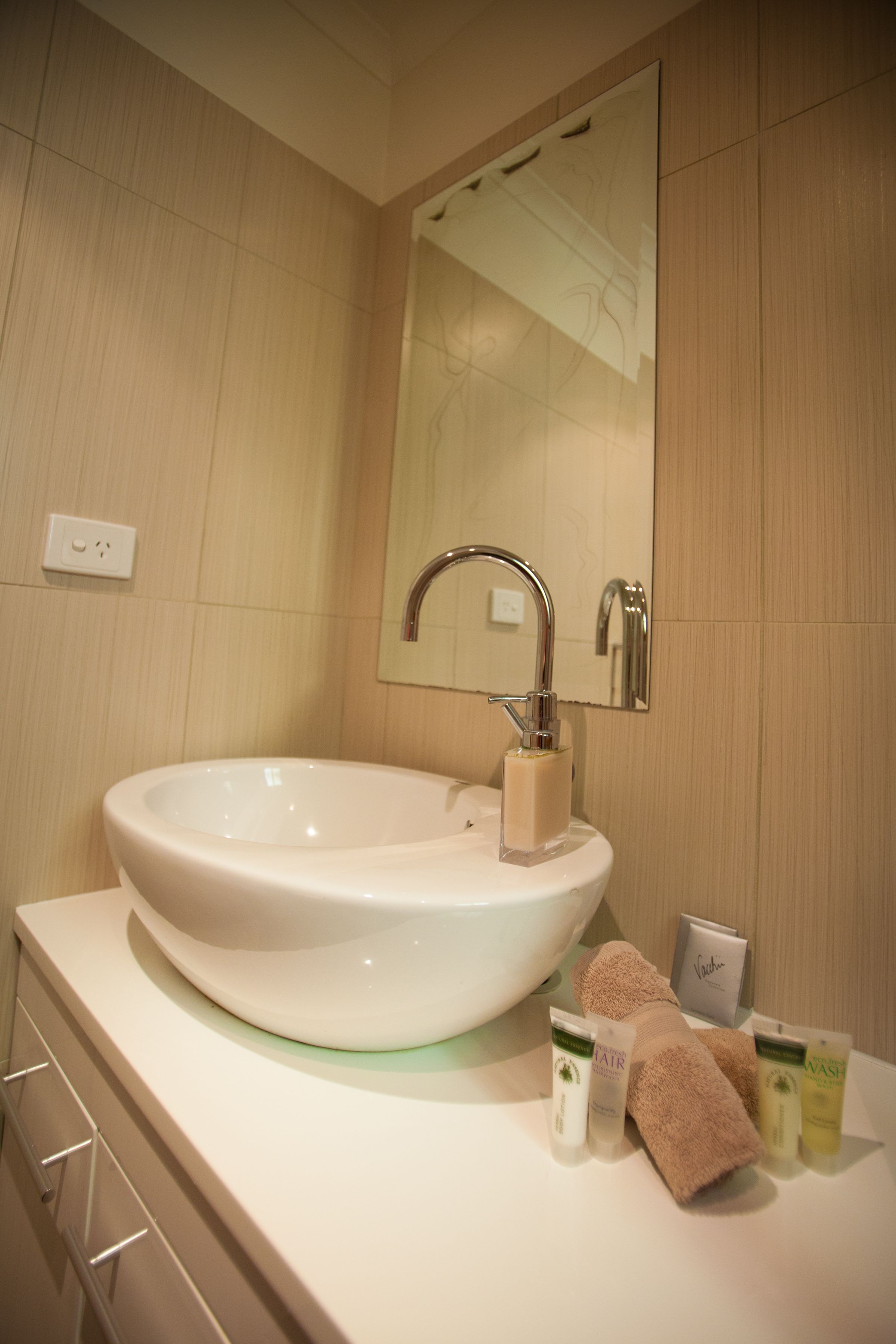 A bathroom with a large white sink, a mirror above it, and toiletries on the counter.