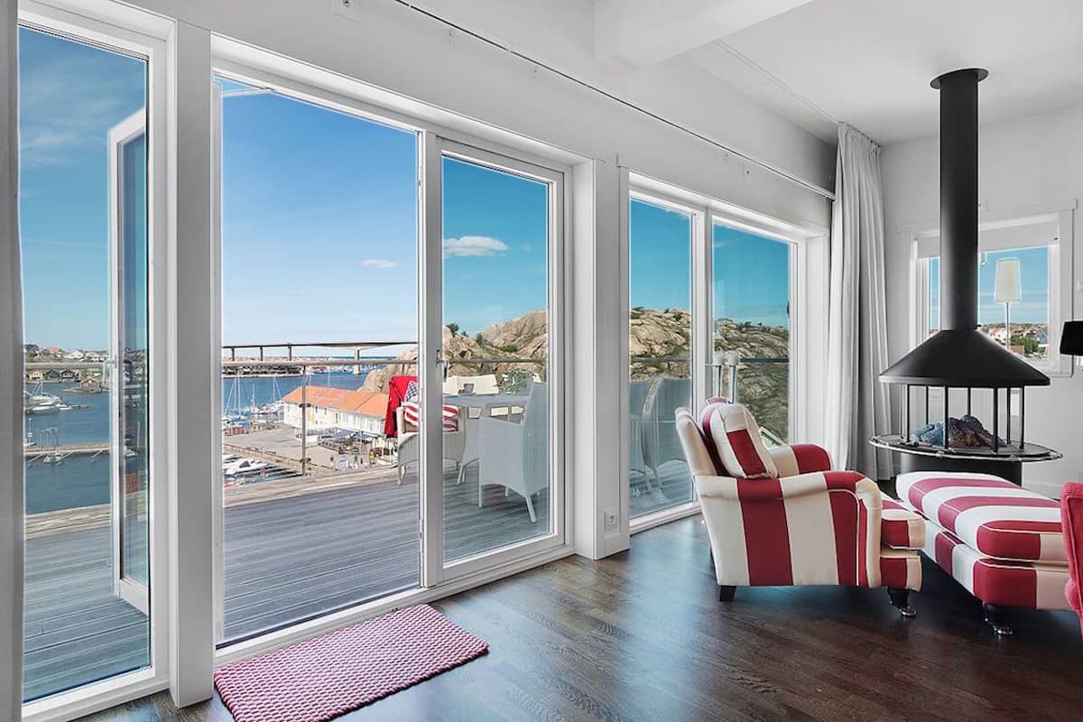 A modern living room with large sliding glass doors, a black fireplace, and a view of a marina.