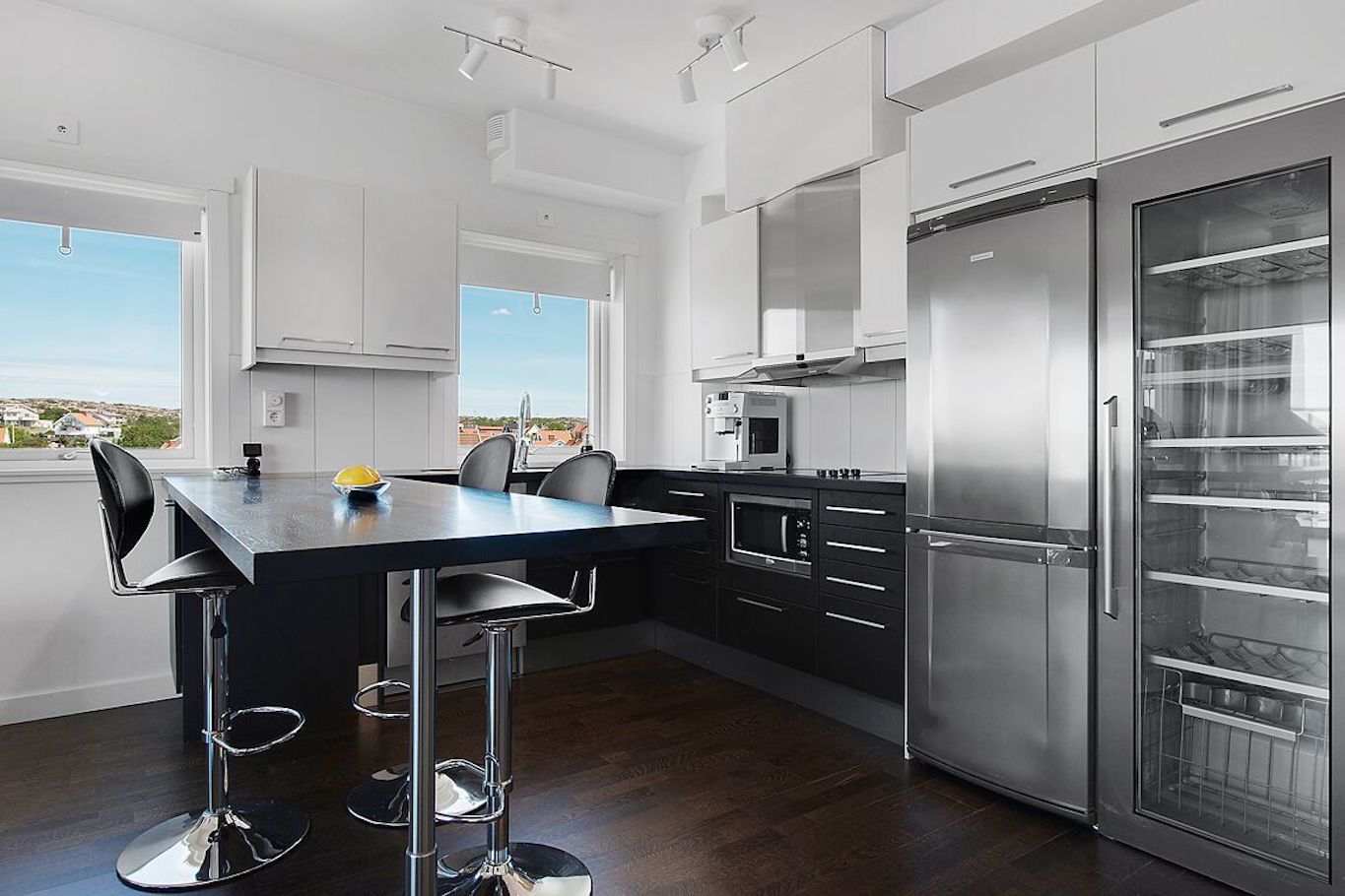 A modern kitchen with a central island, stainless steel appliances, and a view of the city.