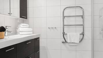 Un bagno moderno con un lavandino bianco, mobili scuri, box doccia in vetro e un appendi asciugamani.