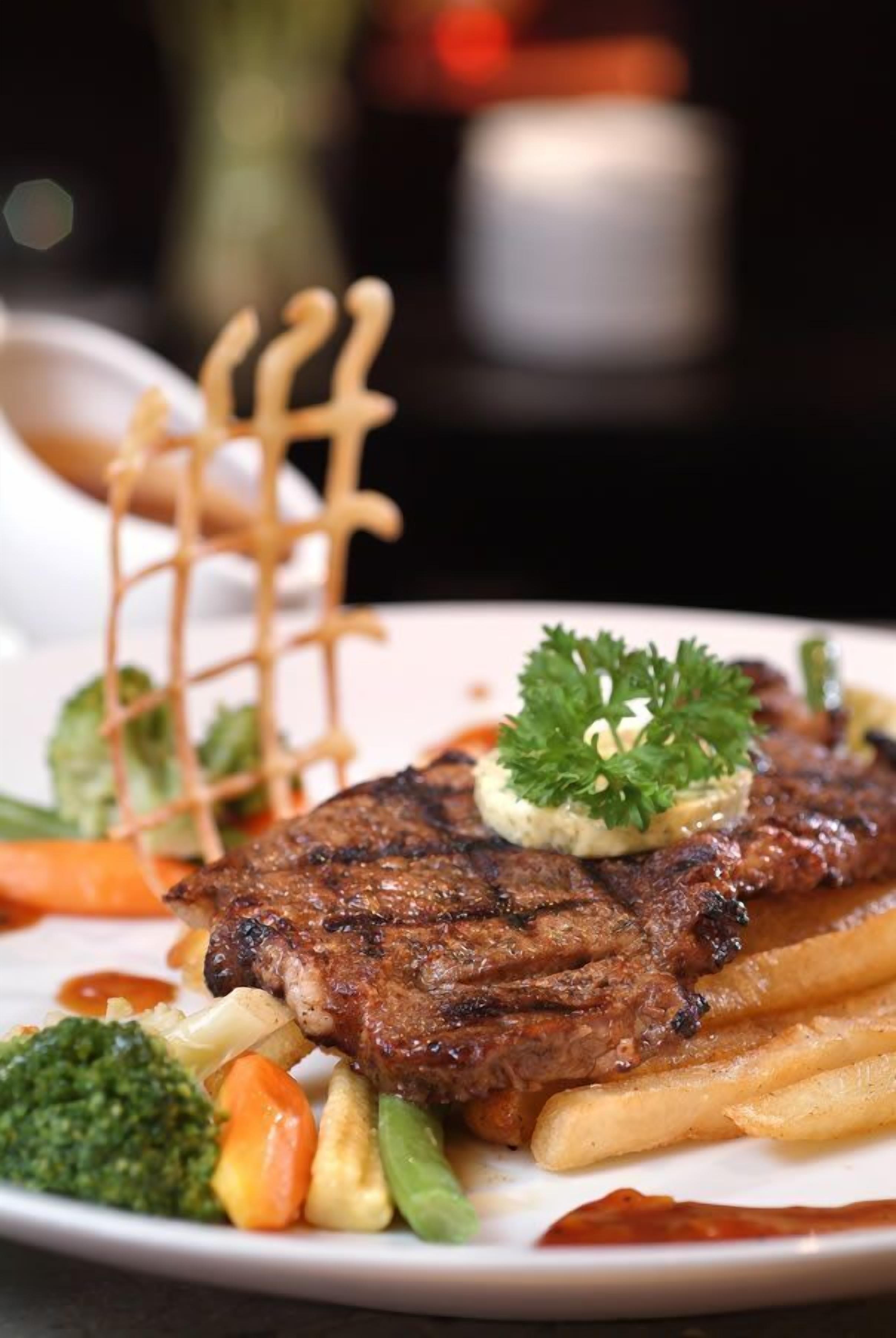 Un plato de carne con verduras y papas fritas.