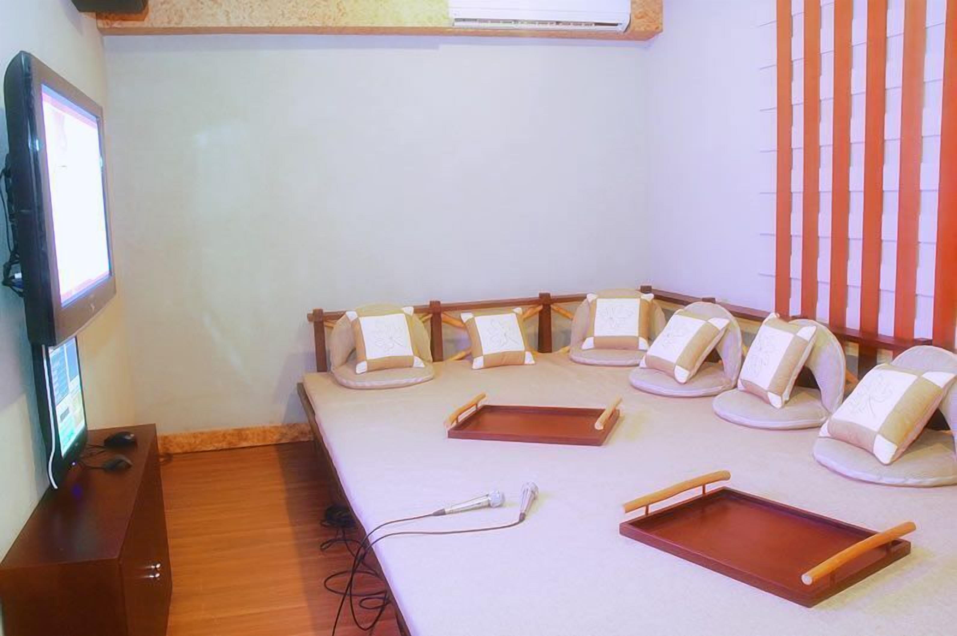Une pièce comprenant une longue table, plusieurs fauteuils confortables, un téléviseur et un microphone.