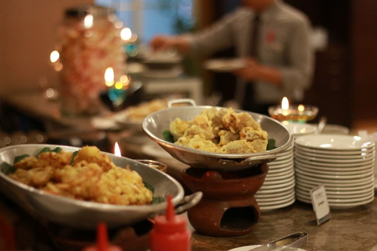 Una mesa de buffet con varios platos, una pila de platos y una vela encendida.