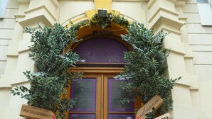 A hostel entrance with a wooden door, two windows, and signs indicating directions to 'Pension Hostel' and 'Arthur's Hostel'. - Artharmony Pension & Hostel (Prague)