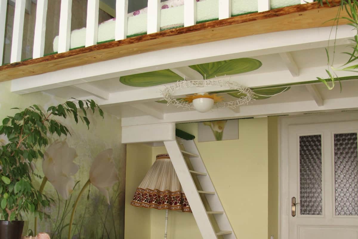 Un dormitorio con cama tipo loft, un sofá, una mesita y una escalera.
