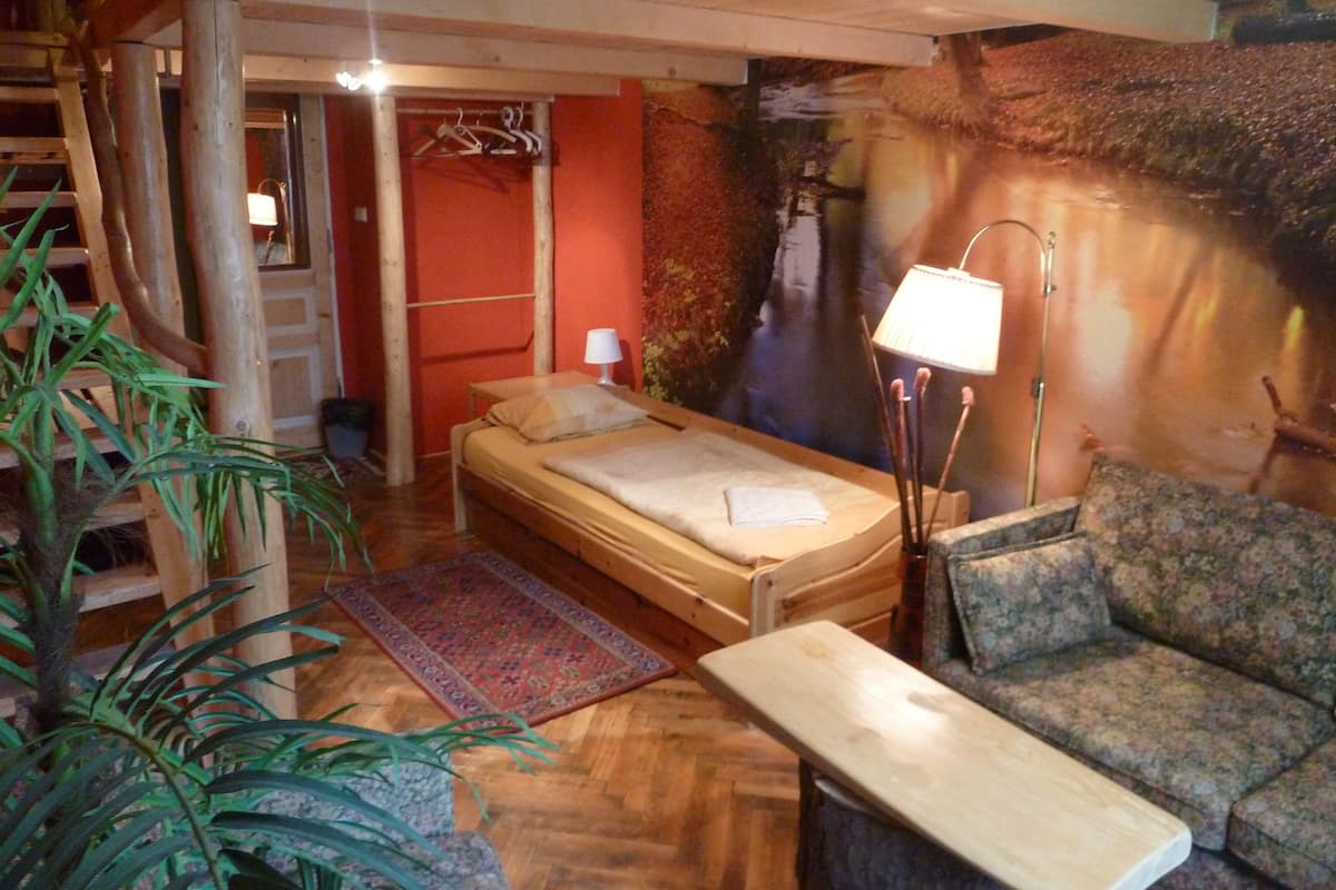 Una habitación con cama, sofá, lámpara y una planta grande.