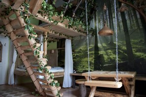 A rustic room with a wooden spiral staircase, a hanging light fixture, and a mural of a forest. - Artharmony Pension & Hostel (Prague)
