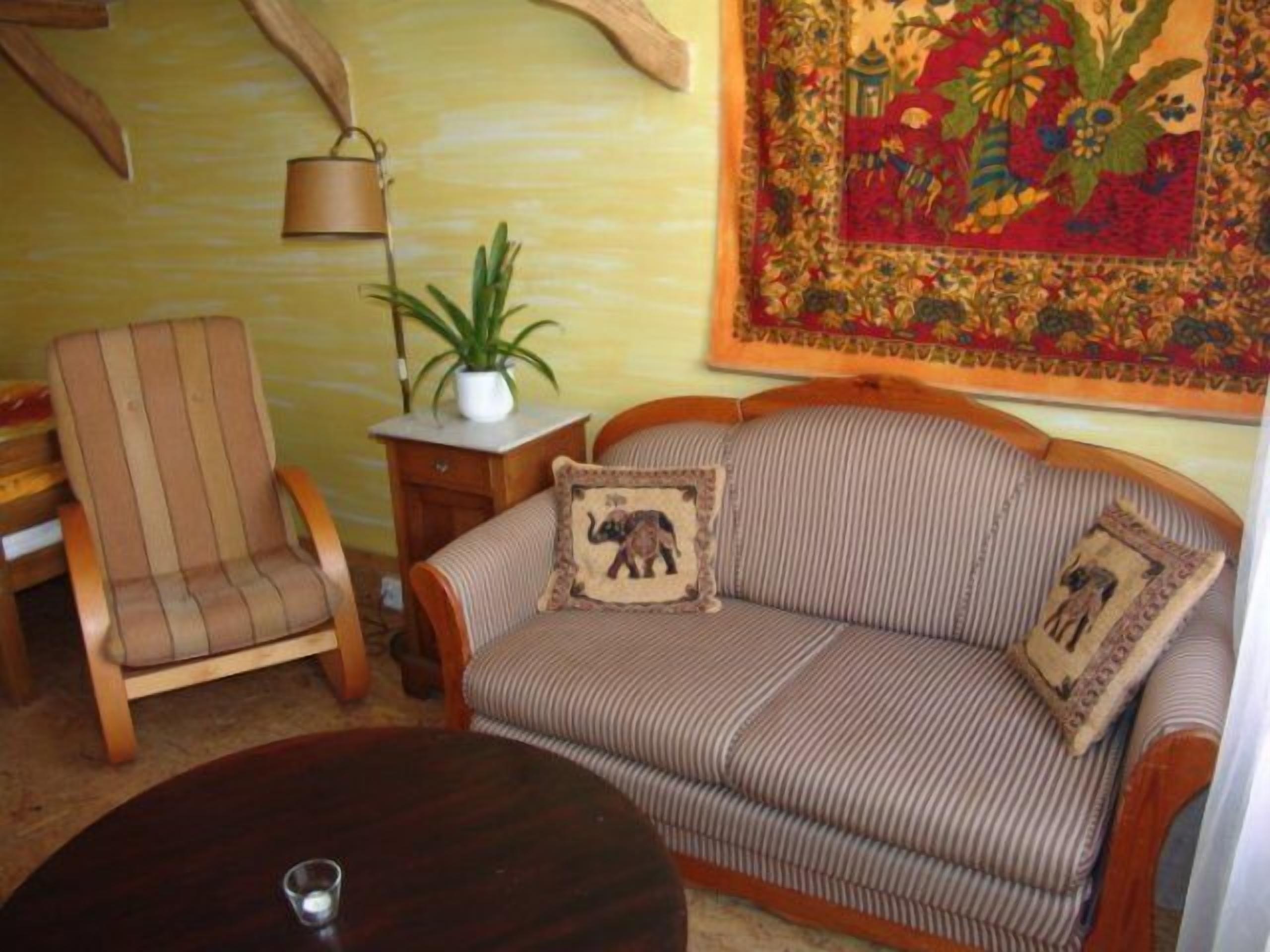 Uma sala de estar aconchegante com um sofá listrado, uma cadeira de madeira, uma mesinha e um tapete decorativo.