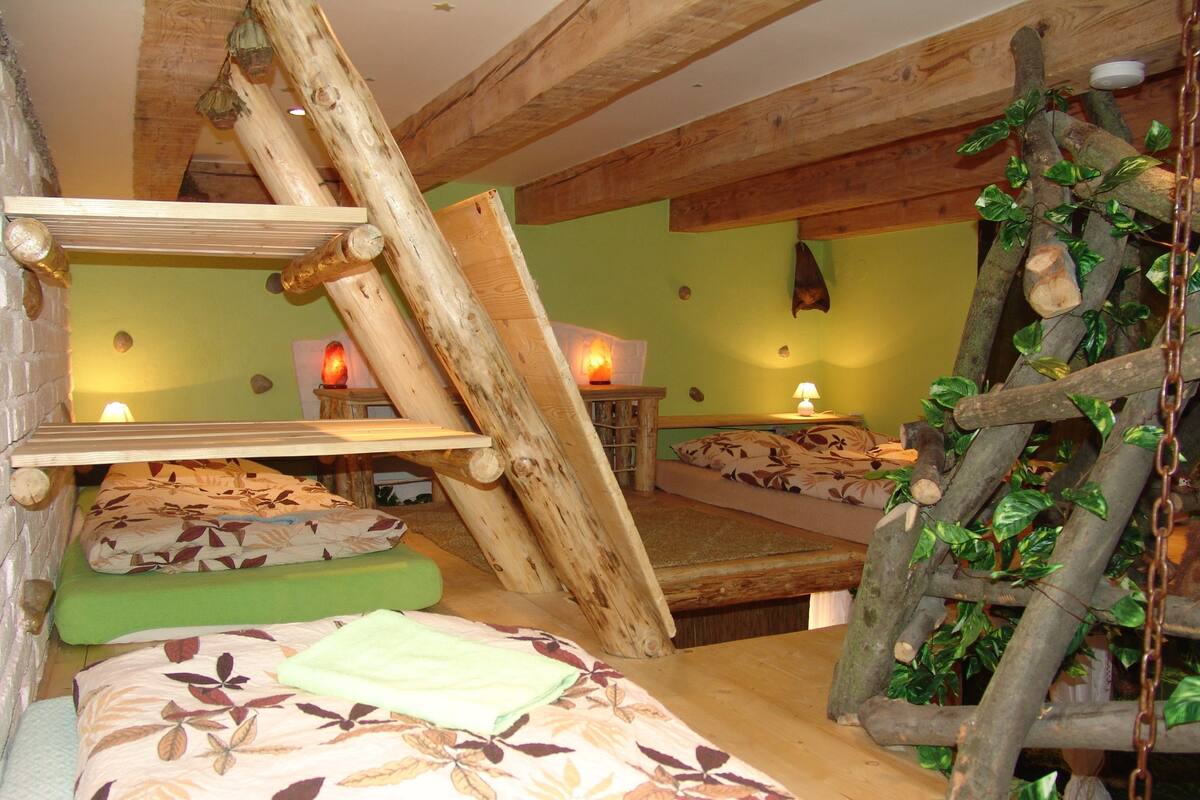 Un dormitorio rústico con una cama estilo altillo, un pequeño sofá y una escalera.