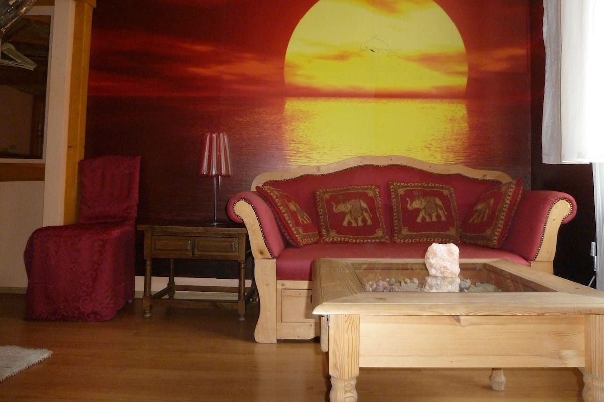 Una sala de estar con un sofá rojo, una mesa de centro de madera y un sillón rojo.