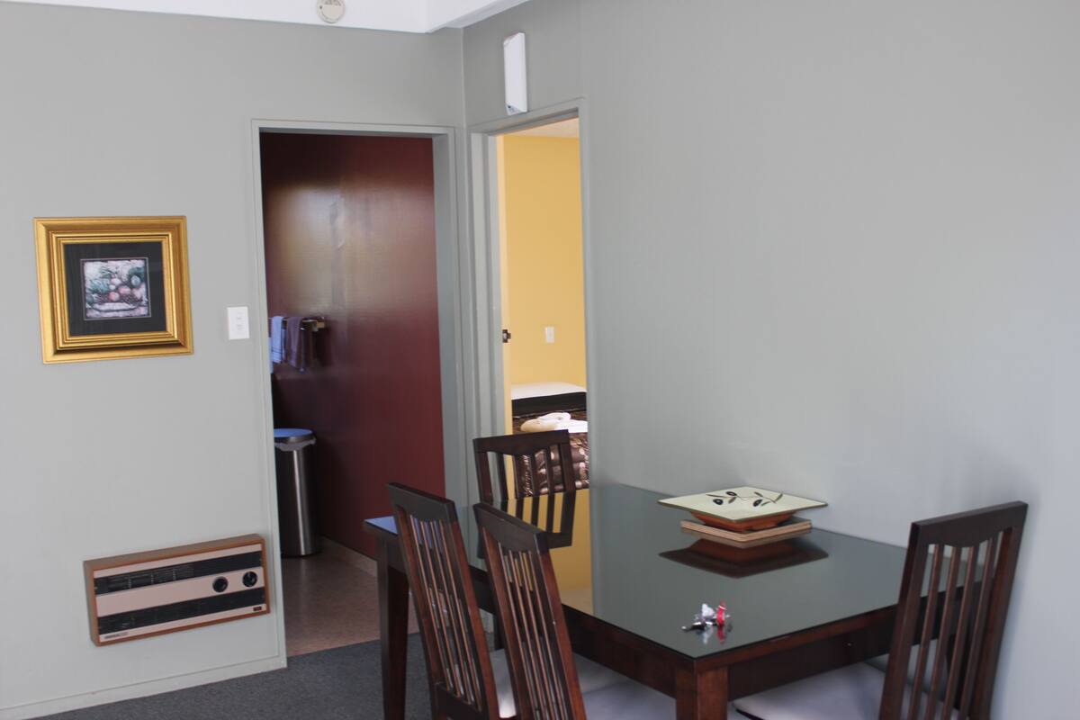 Un coin repas avec une table, des chaises et un tableau encadré au mur.
