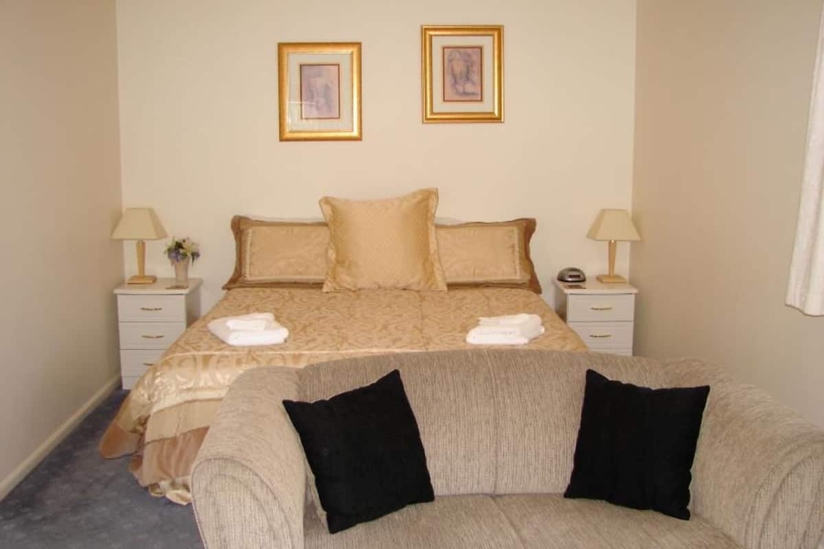 Une chambre à coucher bien rangée, avec un lit, deux tables de chevet et deux tableaux encadrés accrochés au mur.