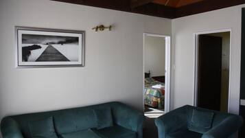 Ein Zimmer mit einem grünen Sofa, einem grünen Sessel und einem gerahmten Bild einer Pier auf der Wand.