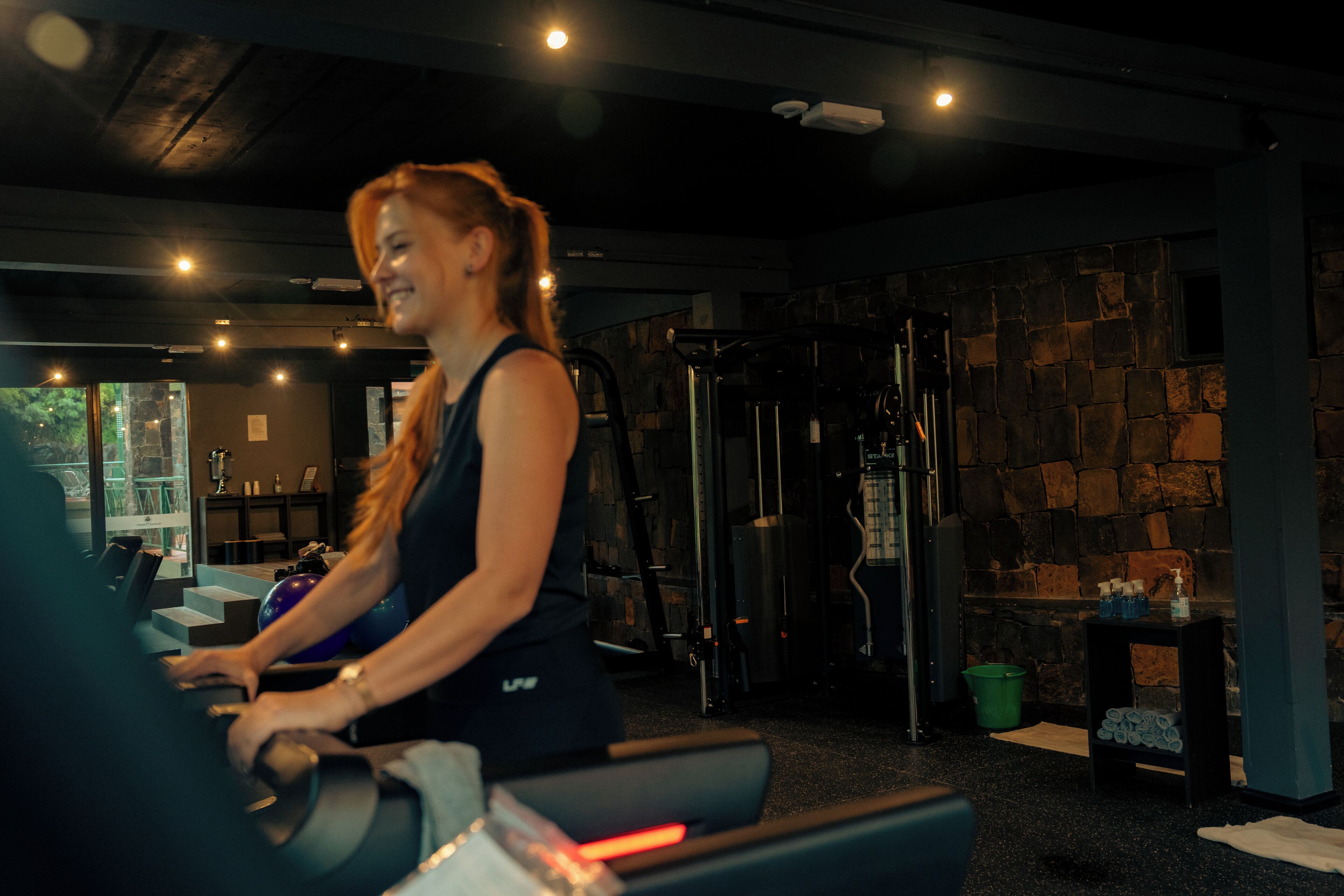 Een sportschool met trainingsapparatuur, een stenen muur en een raam.