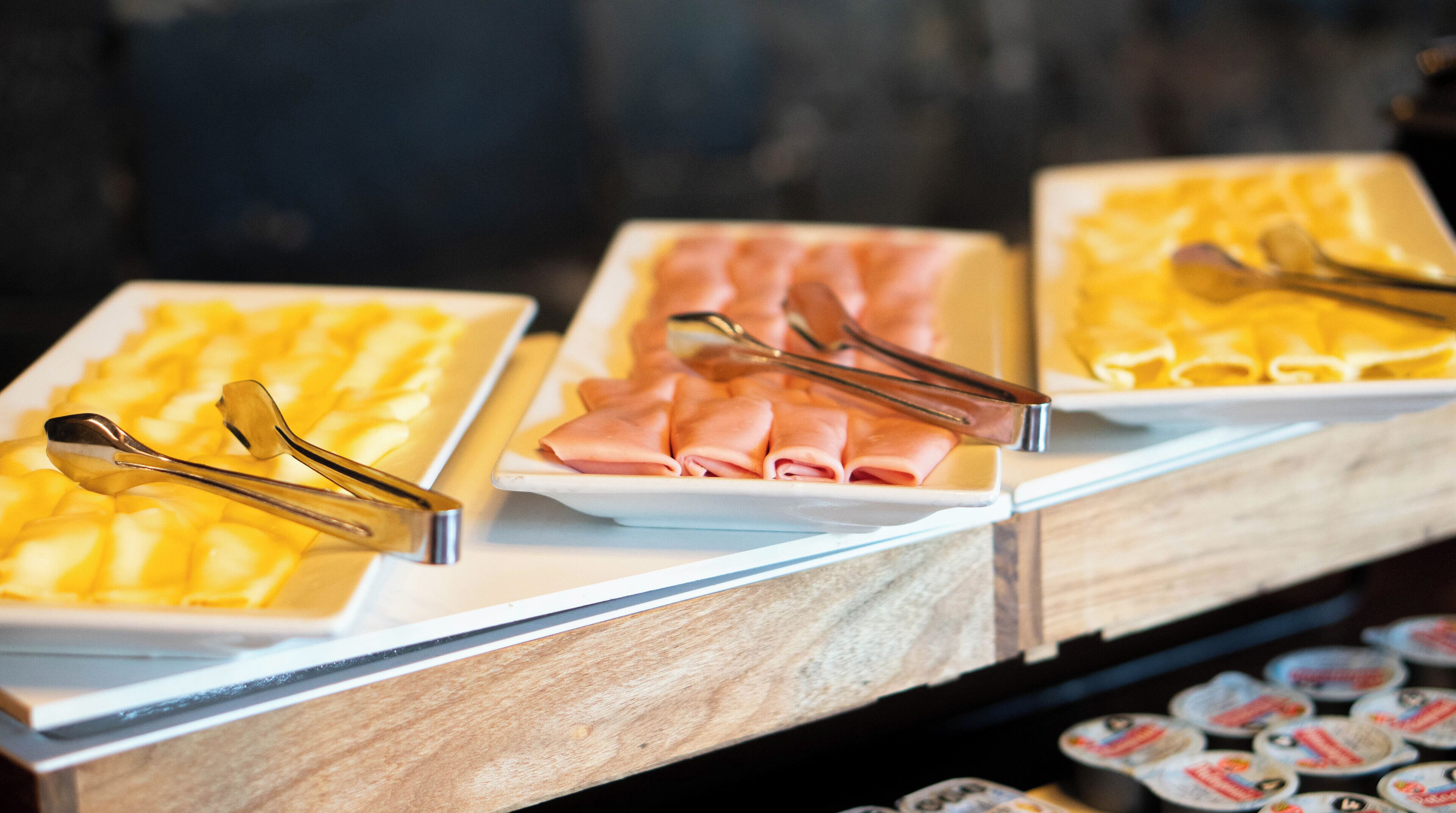 A buffet with various food items, including yellow and pink dishes, arranged on a counter.