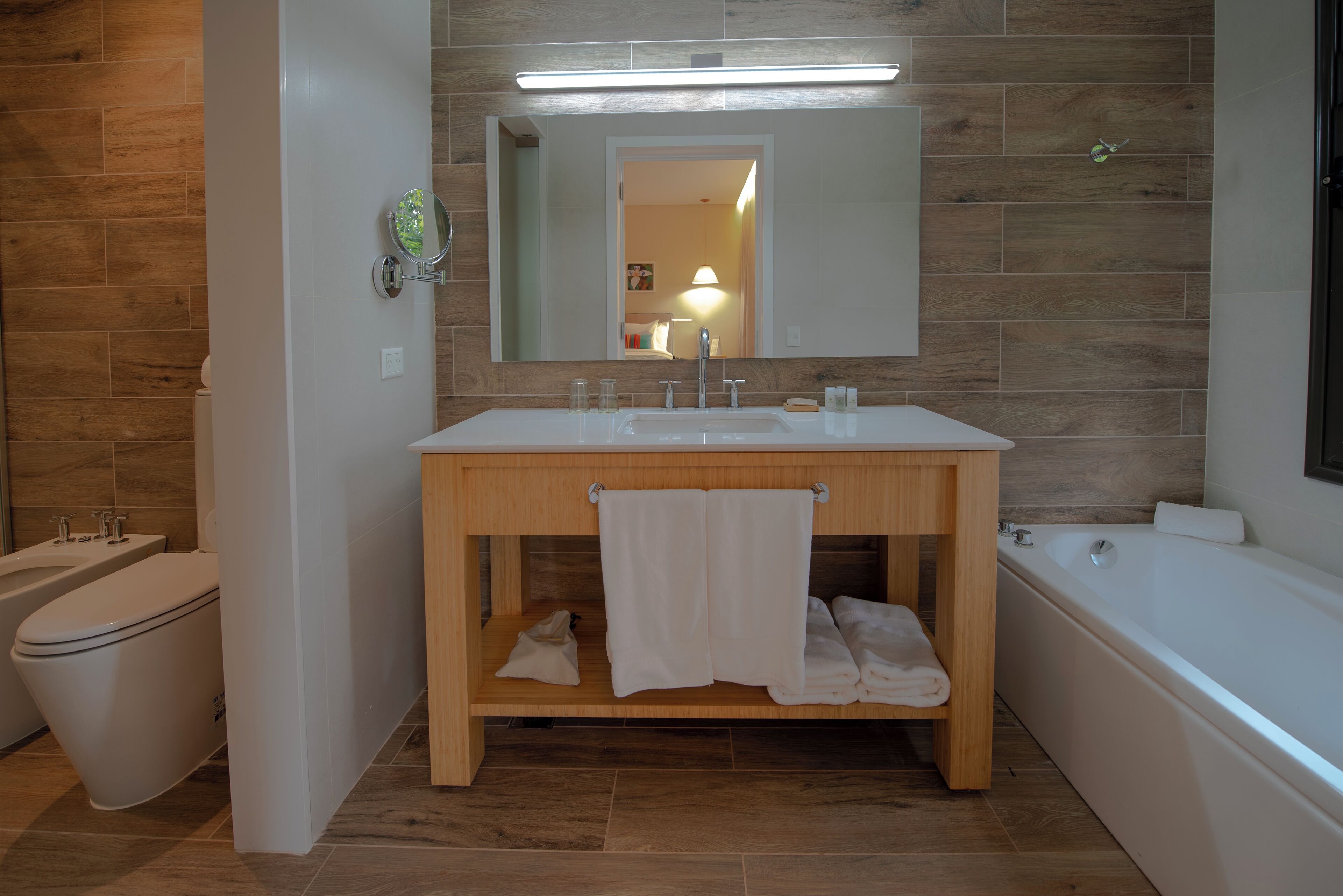 Een moderne badkamer met een houten wastafel, een bad en een toilet.