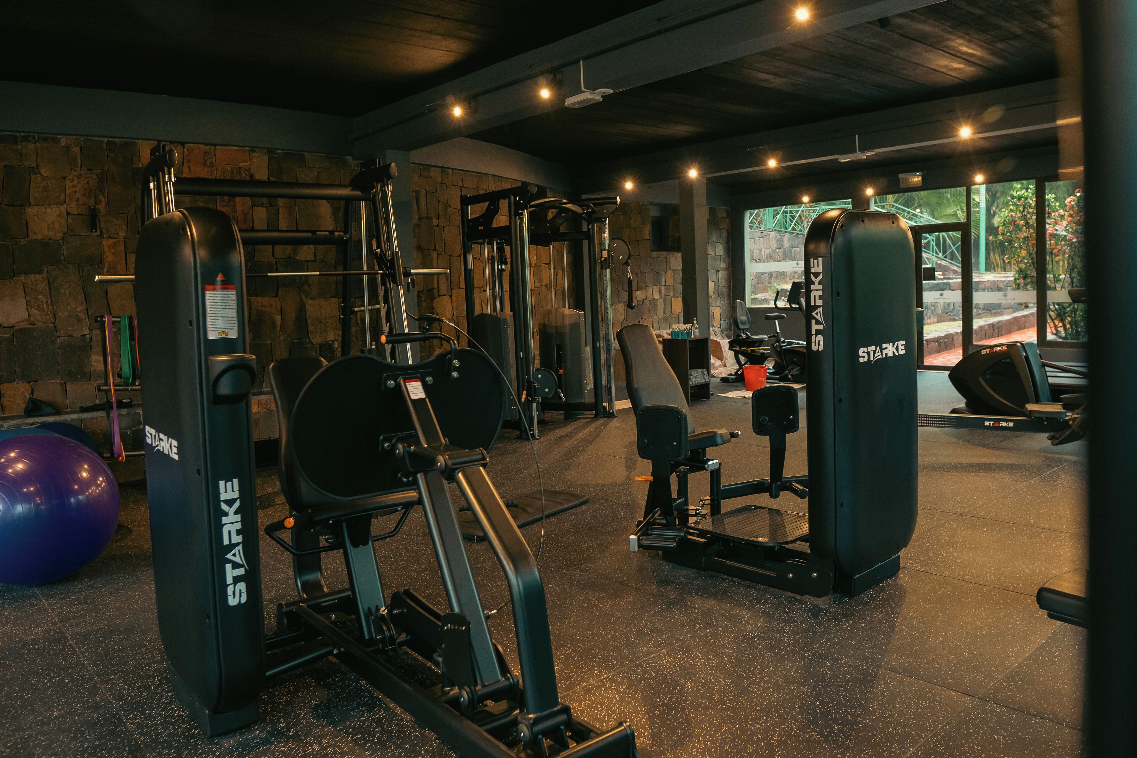 Ein Fitnessstudio mit verschiedenen Trainingsgeräten, darunter ein Squat-Rack und eine Langhantelbank.