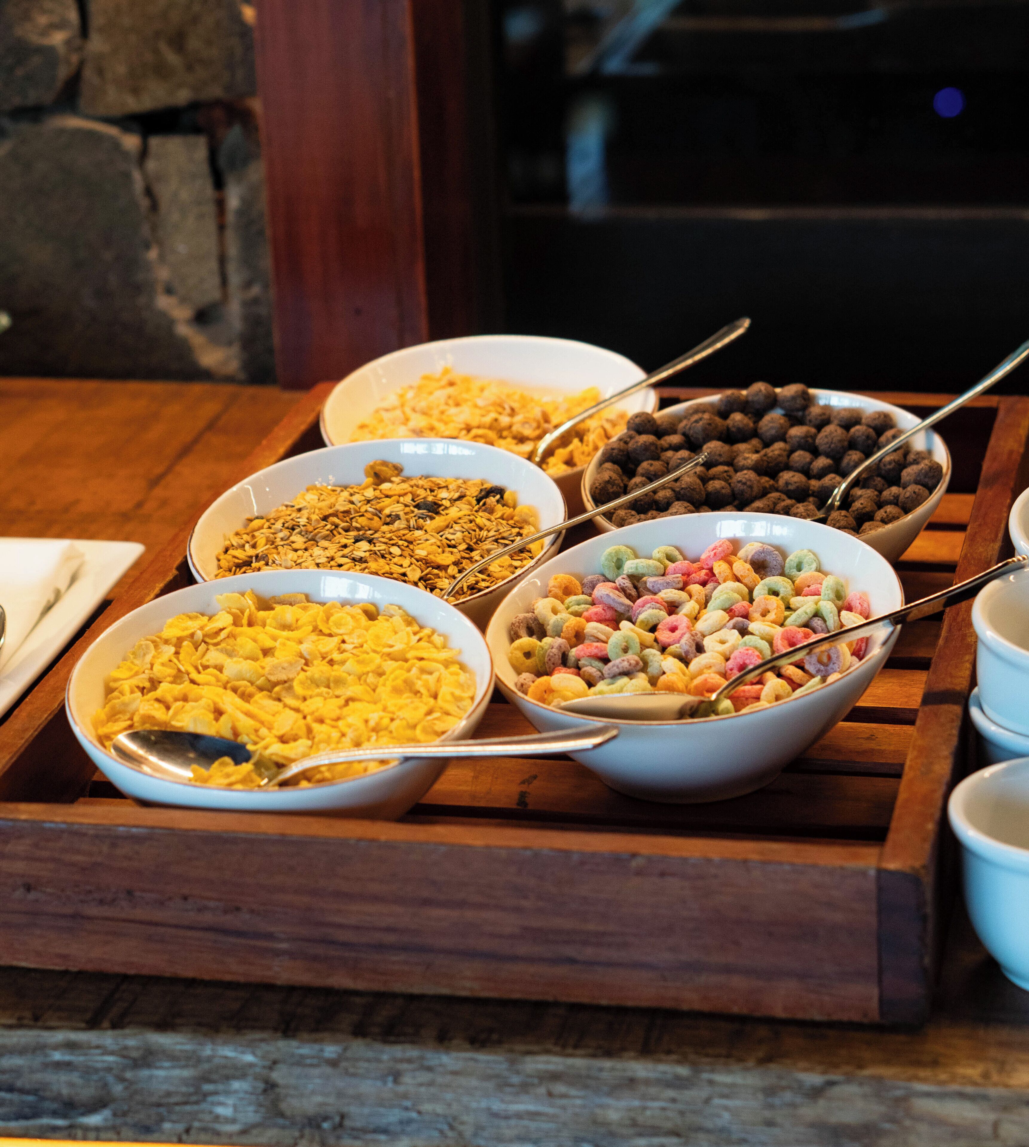 A wooden tray with various bowls of cereal.